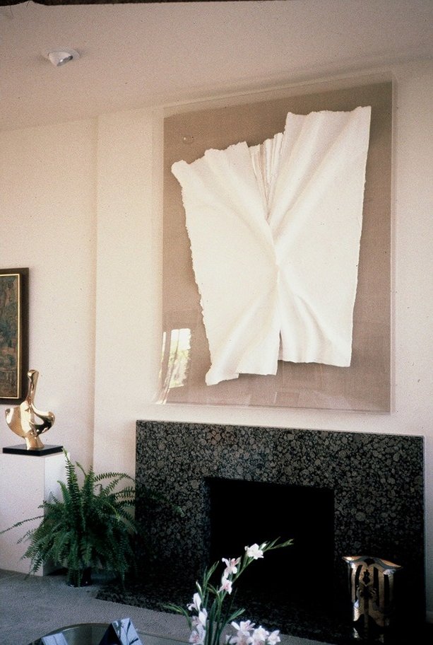 The same piece, above a marble fireplace, surrounded by other artworks.